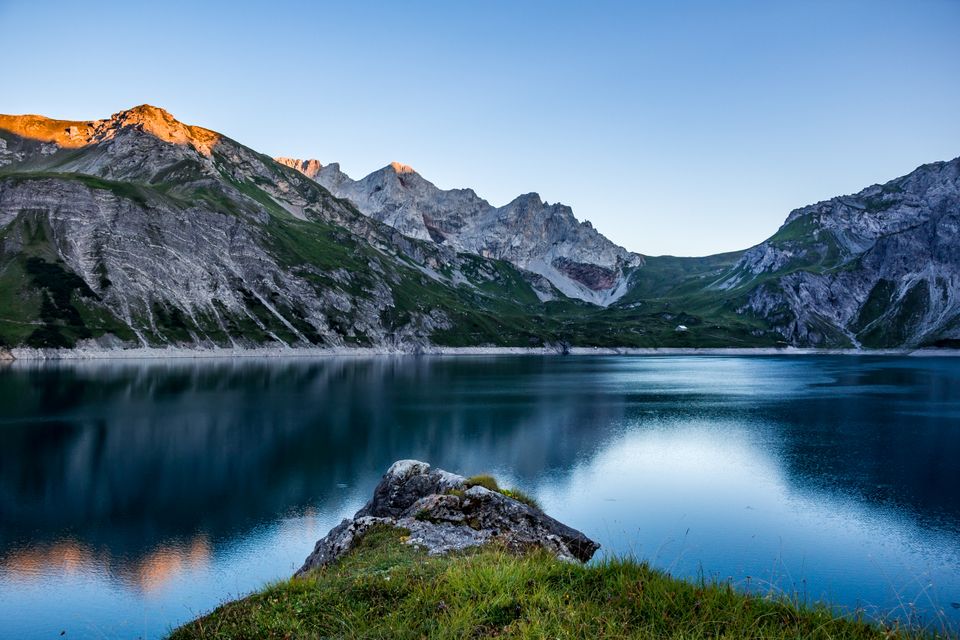 Still blue water below sunlit alpine peaks